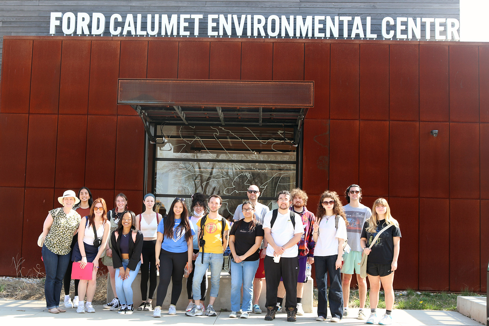 A group of students and professors stand under a sign for the Ford Calument River Center