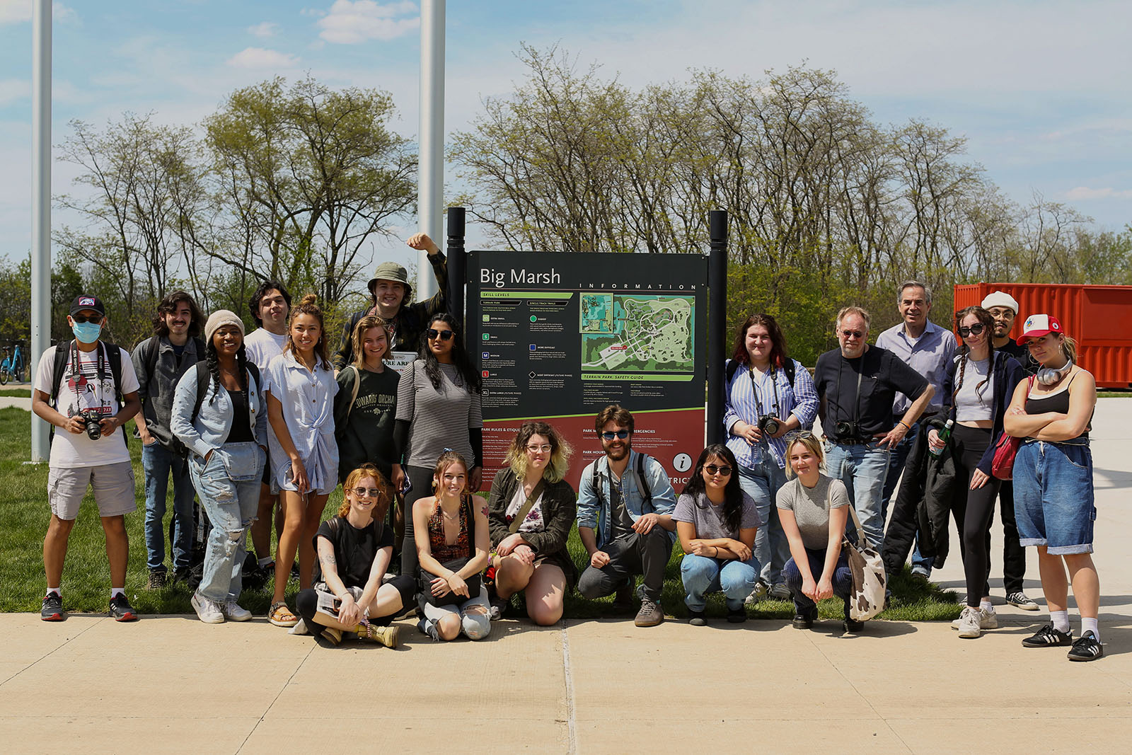 A large group of students and professors pose by an informational sign for Big Marsh Park