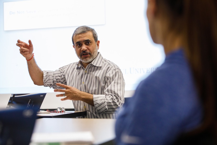 Professor Rajit Mazumder speaking in front of a dry erase board