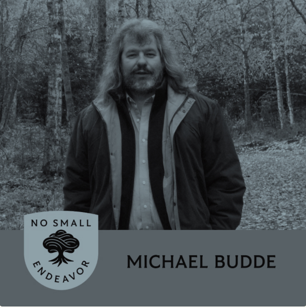 Michael Budde in forest with “No Small Endeavor” logo